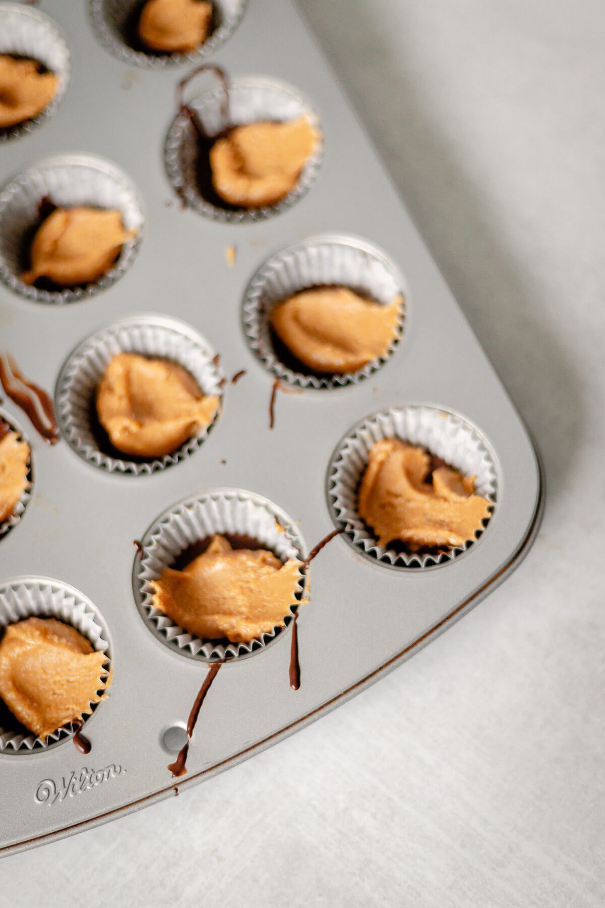 putting peanut butter in the muffin tins for homemade peanut butter cups with dark chocolate