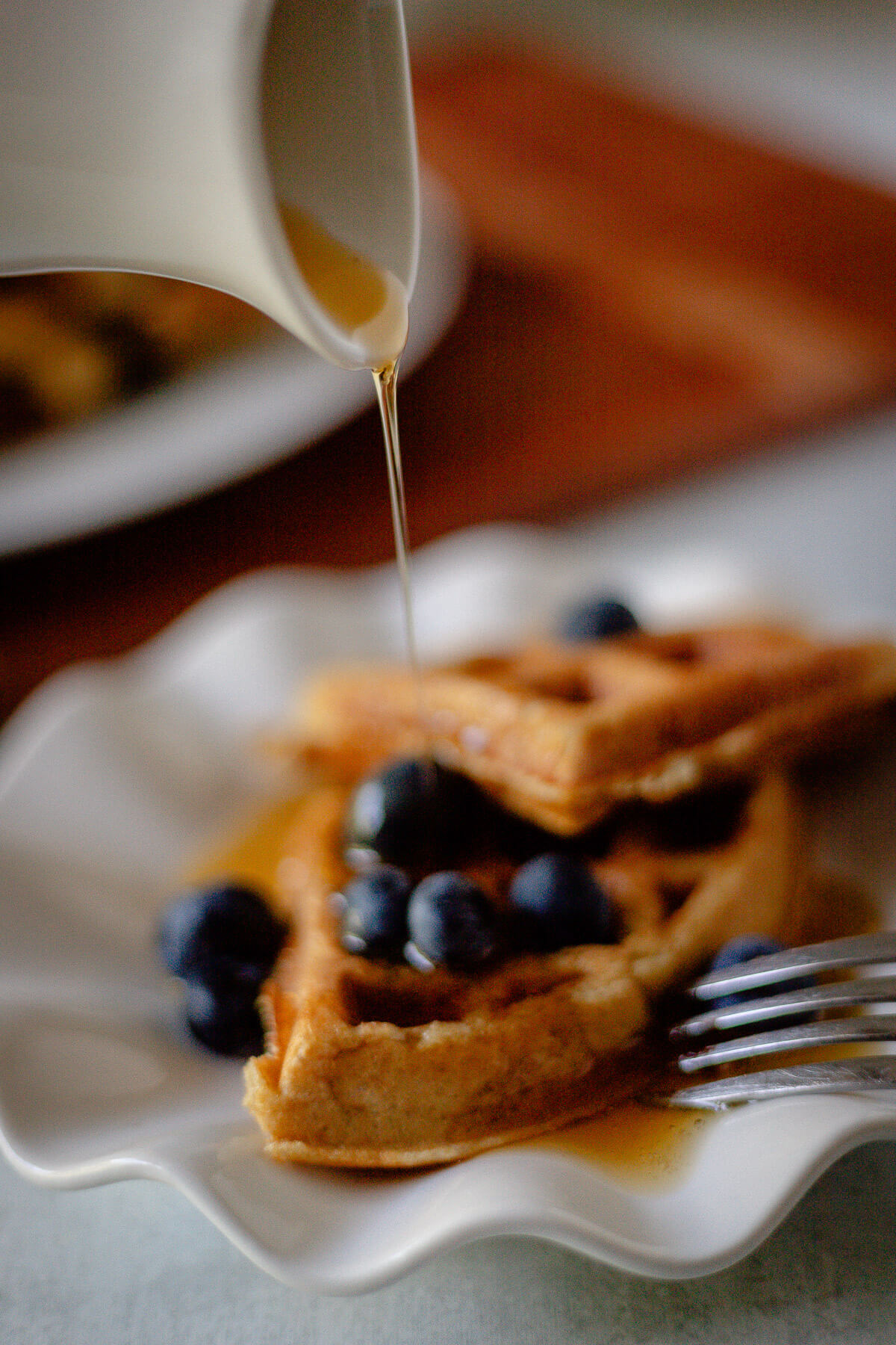 Gluten Free Protein Waffles pouring syrup over gluten free protein waffles with blueberries