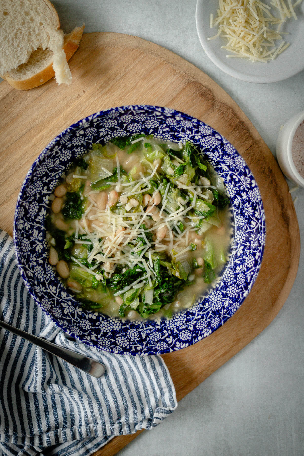 white bean and escarole soup in a bowl with shredded parmesan cheese sprinkled on top