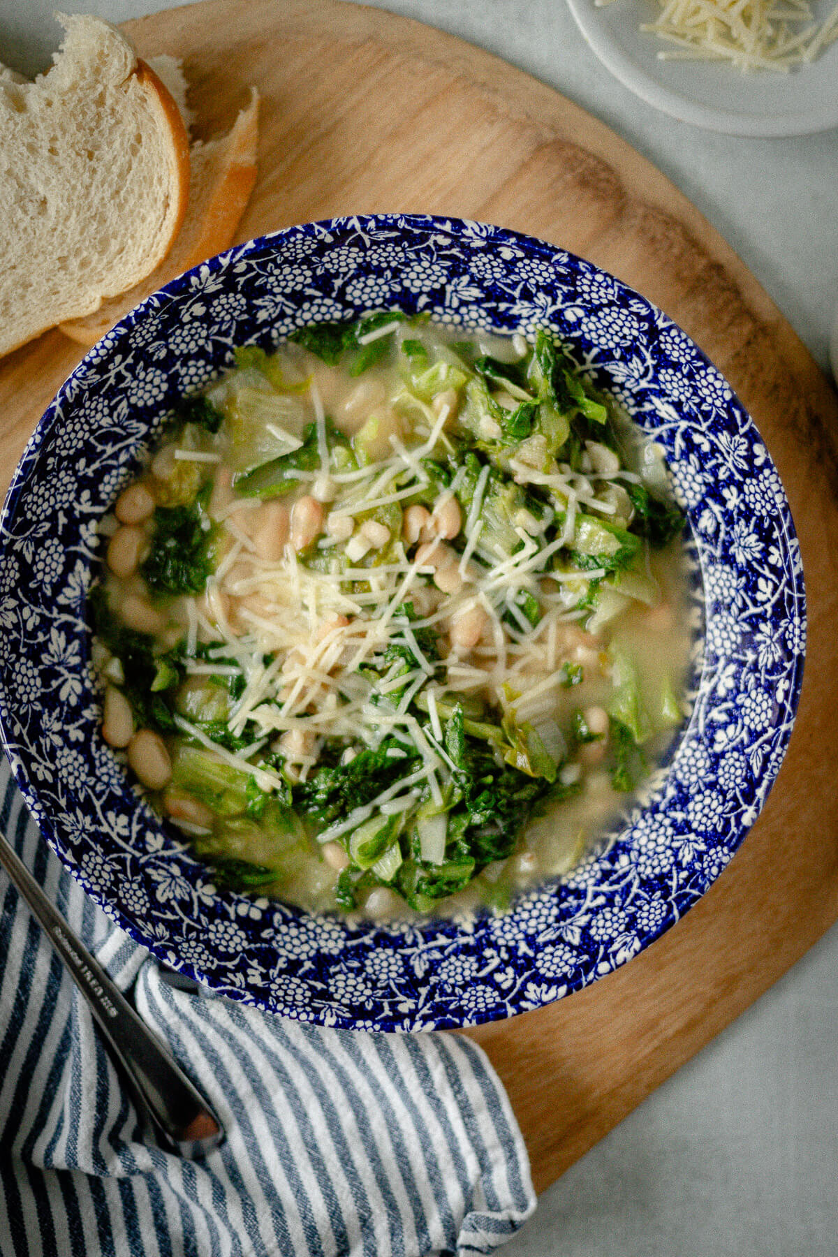 white bean and escarole soup in a bowl with shredded parmesan cheese sprinkled on top