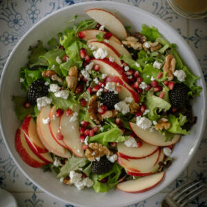 Autumn Harvest Salad with apples goat cheese blackberries walnuts and pomegranate arils.