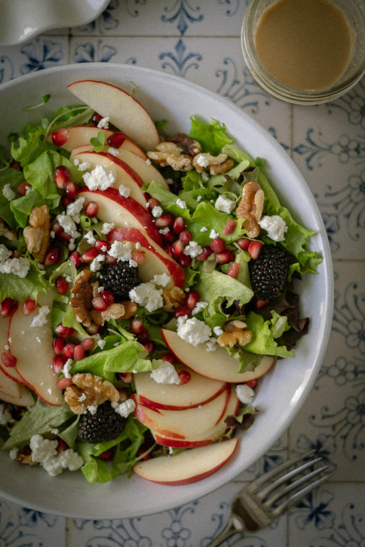 Autumn Harvest Salad with apples goat cheese blackberries walnuts and pomegranate arils. Maple tahini dressing in a jelly jar.