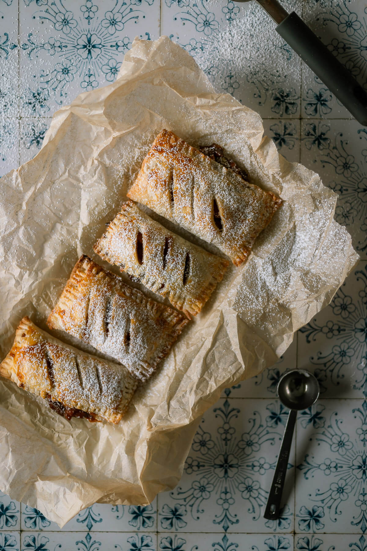 Gluten free apple hand pies on parchment paper dusted with powdered sugar