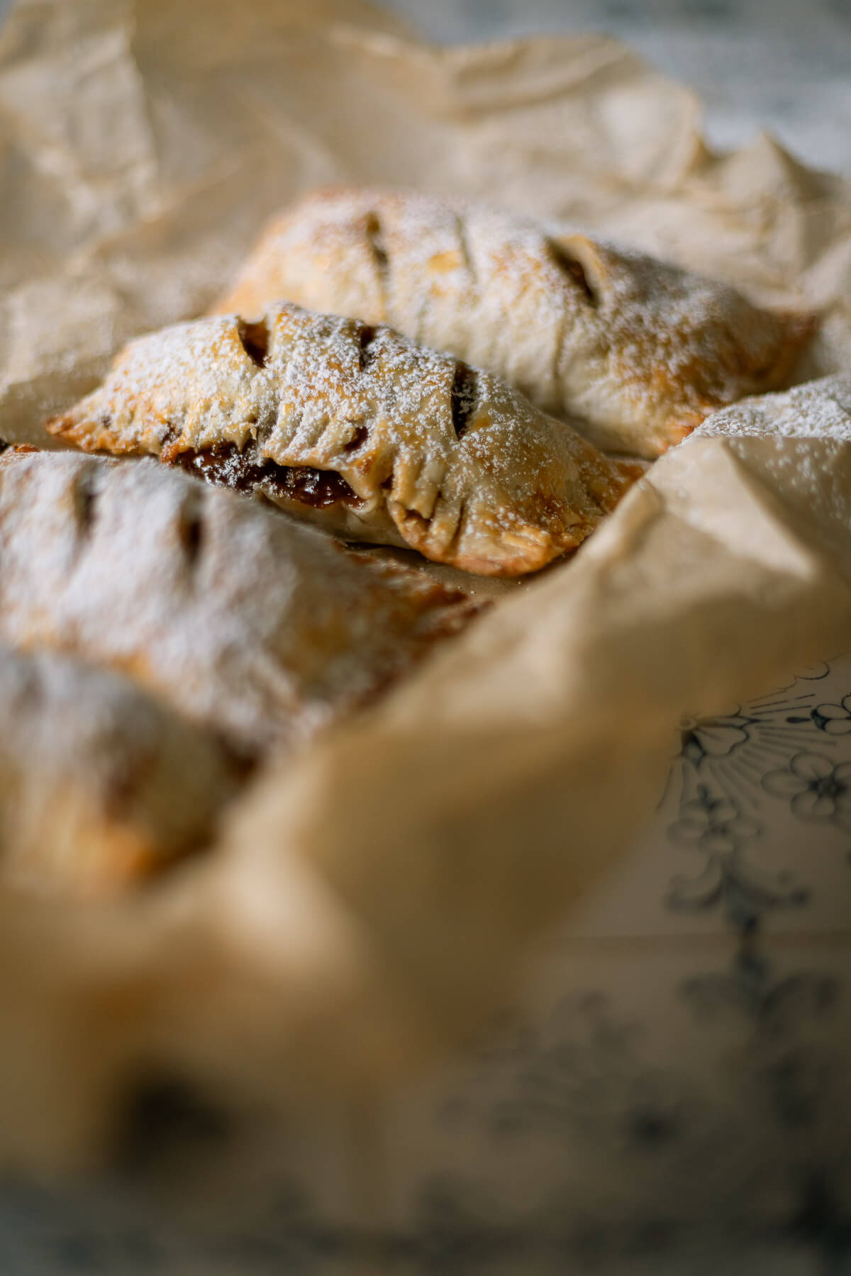 Close up of Gluten free apple hand pies on parchment paper dusted with powdered sugar