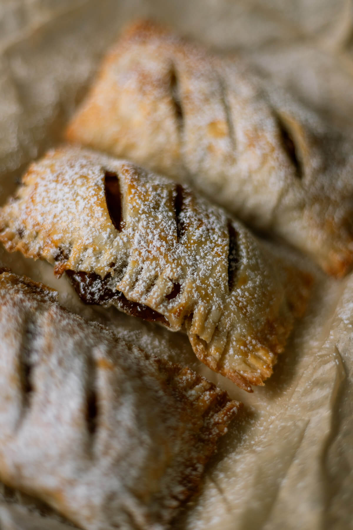 Close up of Gluten free apple hand pies on parchment paper dusted with powdered sugar