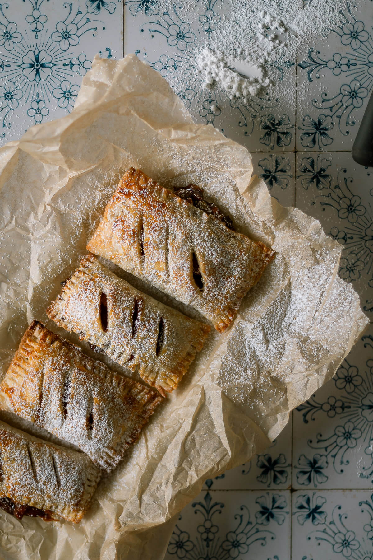 Gluten free apple hand pies on parchment paper dusted with powdered sugar